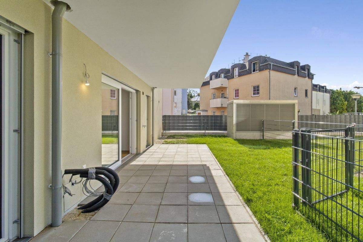 Unmöblierte Terrasse mit direktem Zugang zum Gartenbereich und Blick auf die Umgebung.