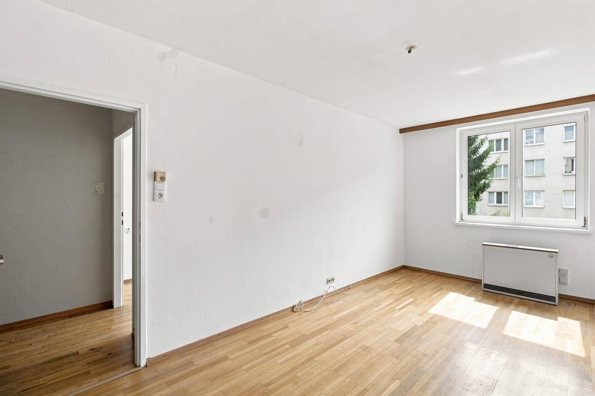 Lichtdurchflutetes Schlafzimmer mit Holzboden und Blick ins Grüne, bereit zur Einrichtung.