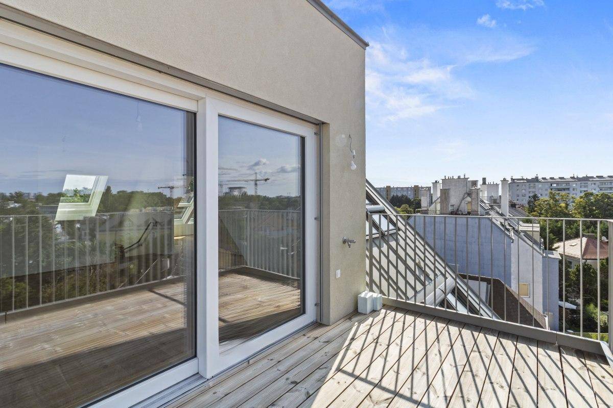 Balkon mit Holzboden und großer Glasschiebetür, die viel Licht in den Innenraum lässt.