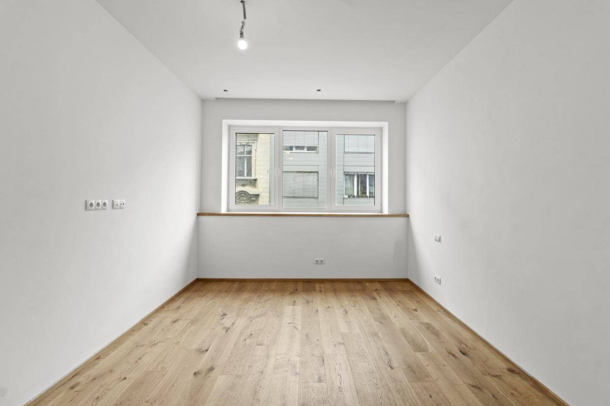 Geräumiges Schlafzimmer mit Holzboden und einem großen Fenster, das für ausreichend Tageslicht sorgt.