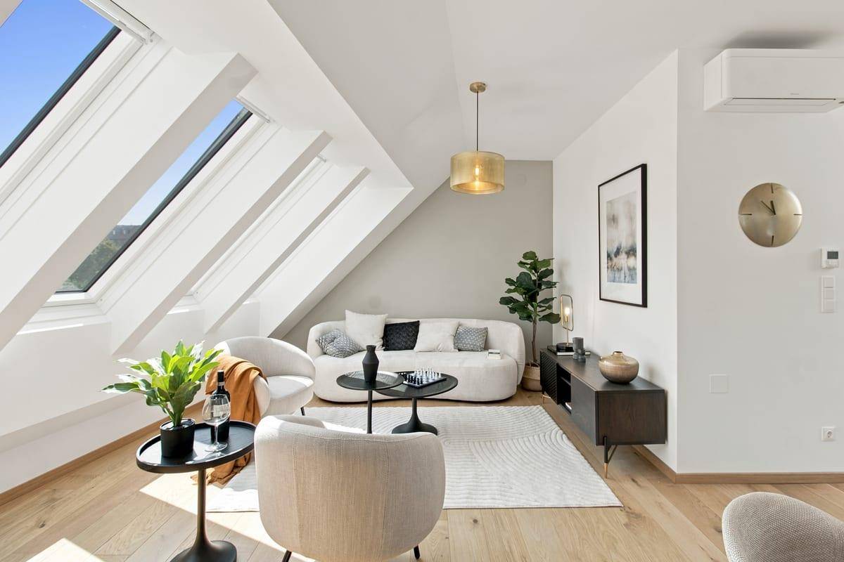 Gemütliches Wohnzimmer mit bequemen Möbeln, Holzboden und großen Dachfenstern.
