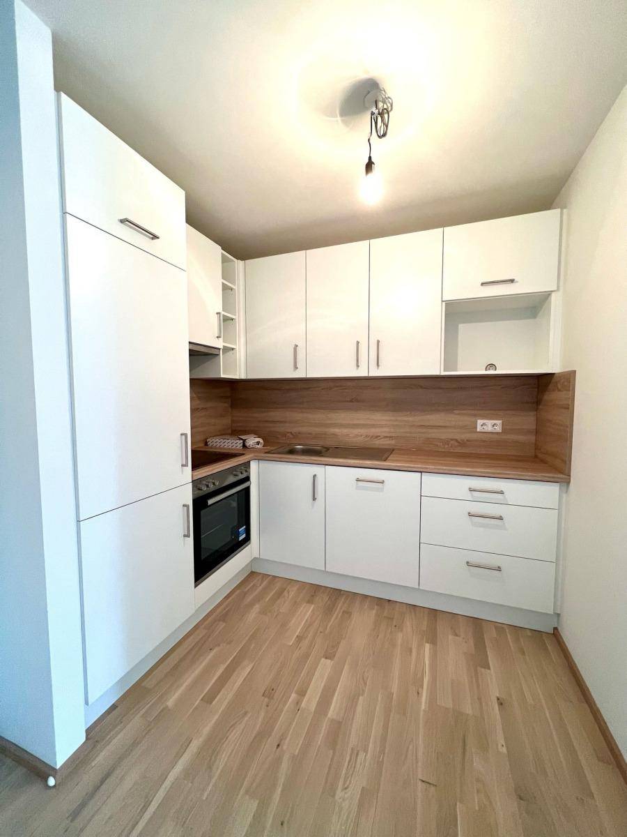 Moderne Einbauküche mit weißen Schränken, Holzoptik-Arbeitsplatte und integriertem Backofen.