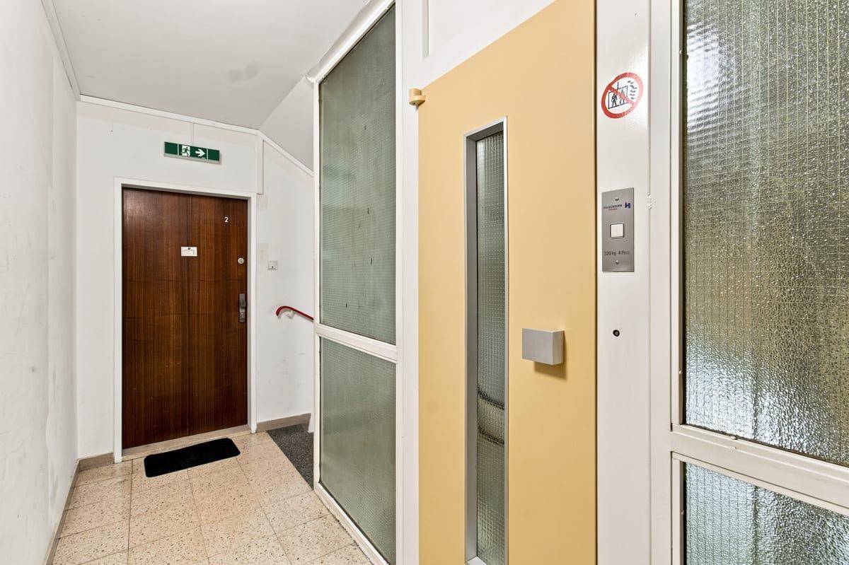 Heller Eingangsbereich mit Aufzug und Zugang zu den Wohnungen, mit Terrazzoboden.