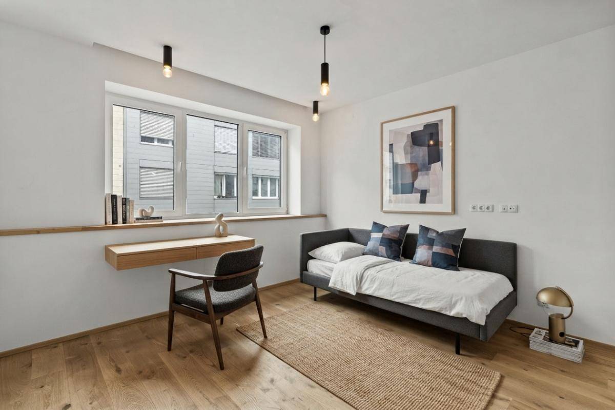 Modernes Schlafzimmer mit Einzelbett, Schreibtisch und Holzboden, ideal als Gästezimmer oder Büro.