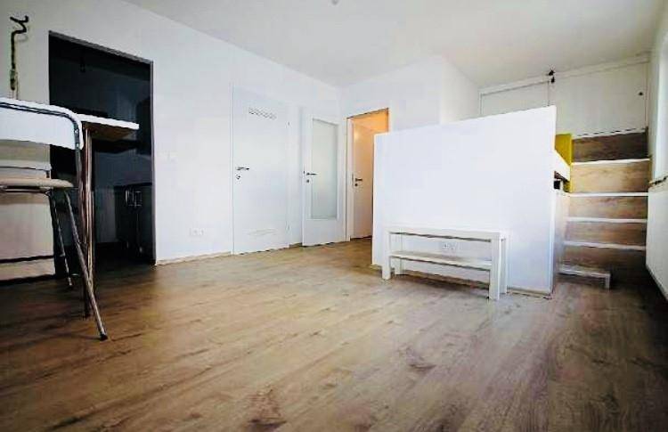 Heller Wohnbereich mit Laminatboden und Zugang zu weiteren Räumen, inklusive Hochbett-Struktur.