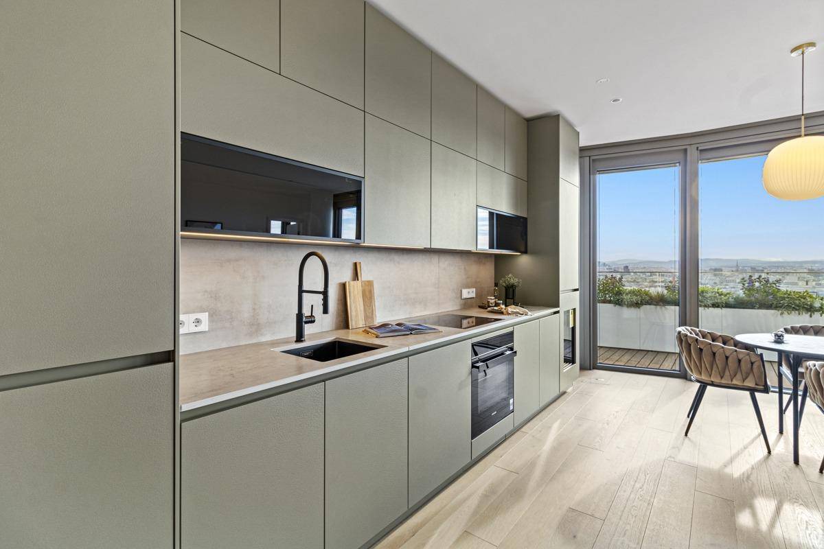 Moderne Küche mit grauen Schränken, integrierten Geräten und Essbereich mit Weitblick.