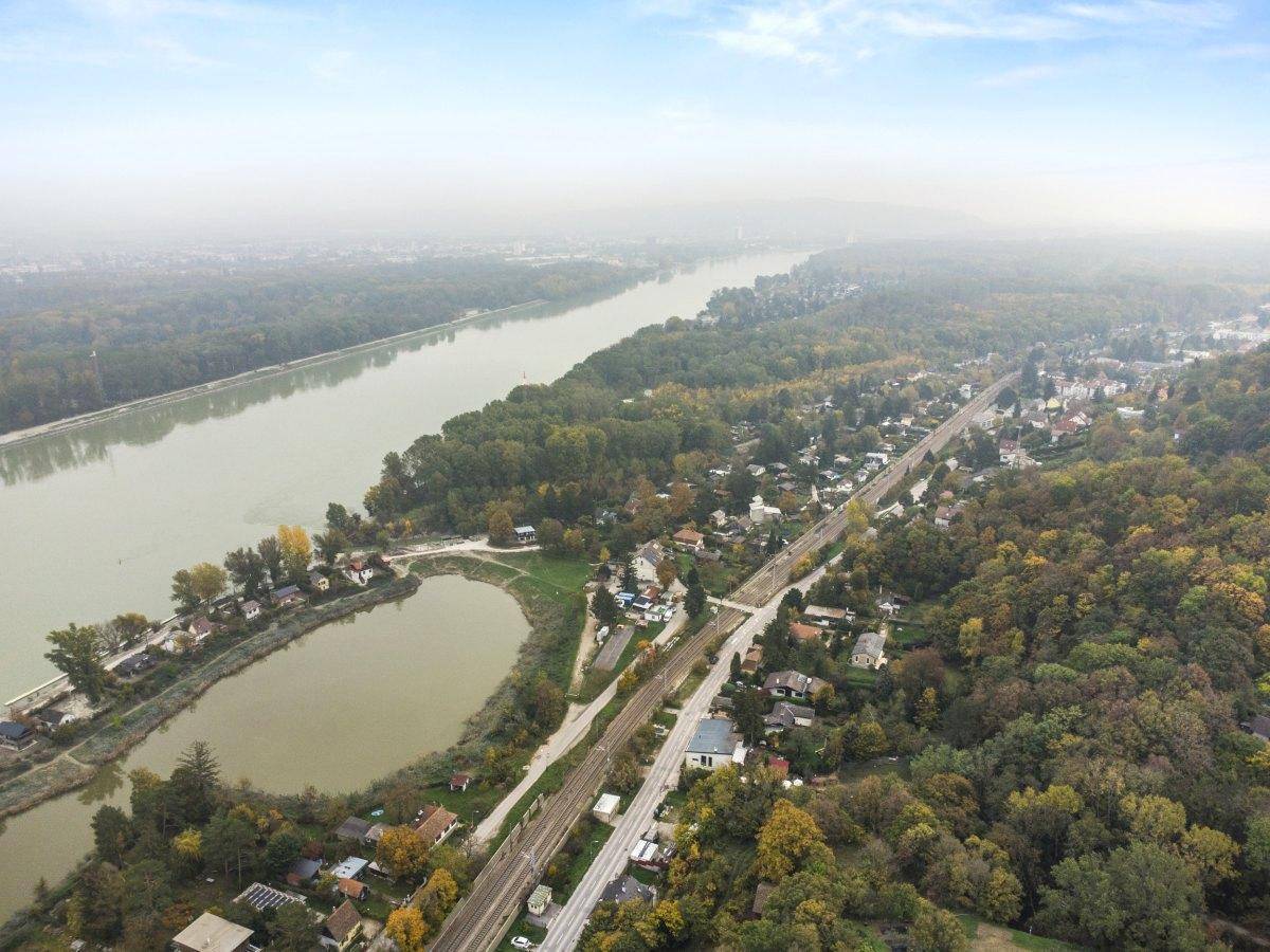 Weitläufige Luftaufnahme der Flusslandschaft mit umliegenden Häusern und Wäldern.