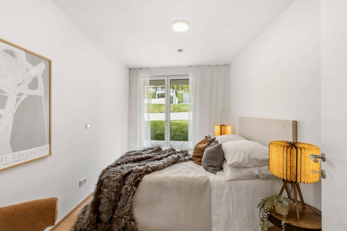 Gemütliches Schlafzimmer mit großem Fenster und Zugang zum Garten, hell und modern eingerichtet.