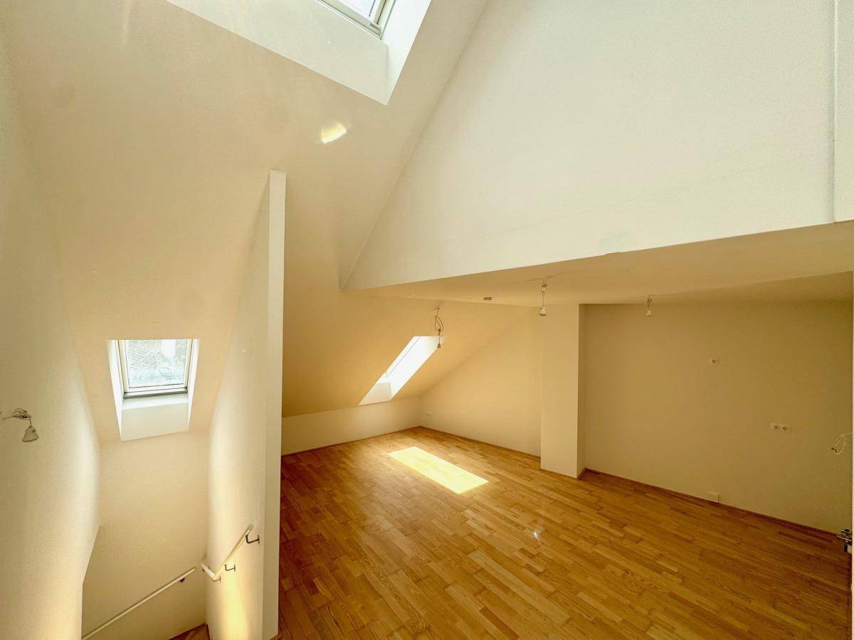 Geräumiger Dachgeschossraum mit Holzboden, mehreren Dachfenstern und offenem Treppenbereich.