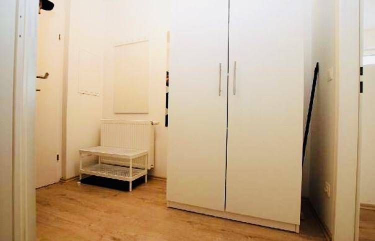 Flur mit weißem Kleiderschrank, Schuhregal und Heizkörper, führt zu weiteren Räumen.