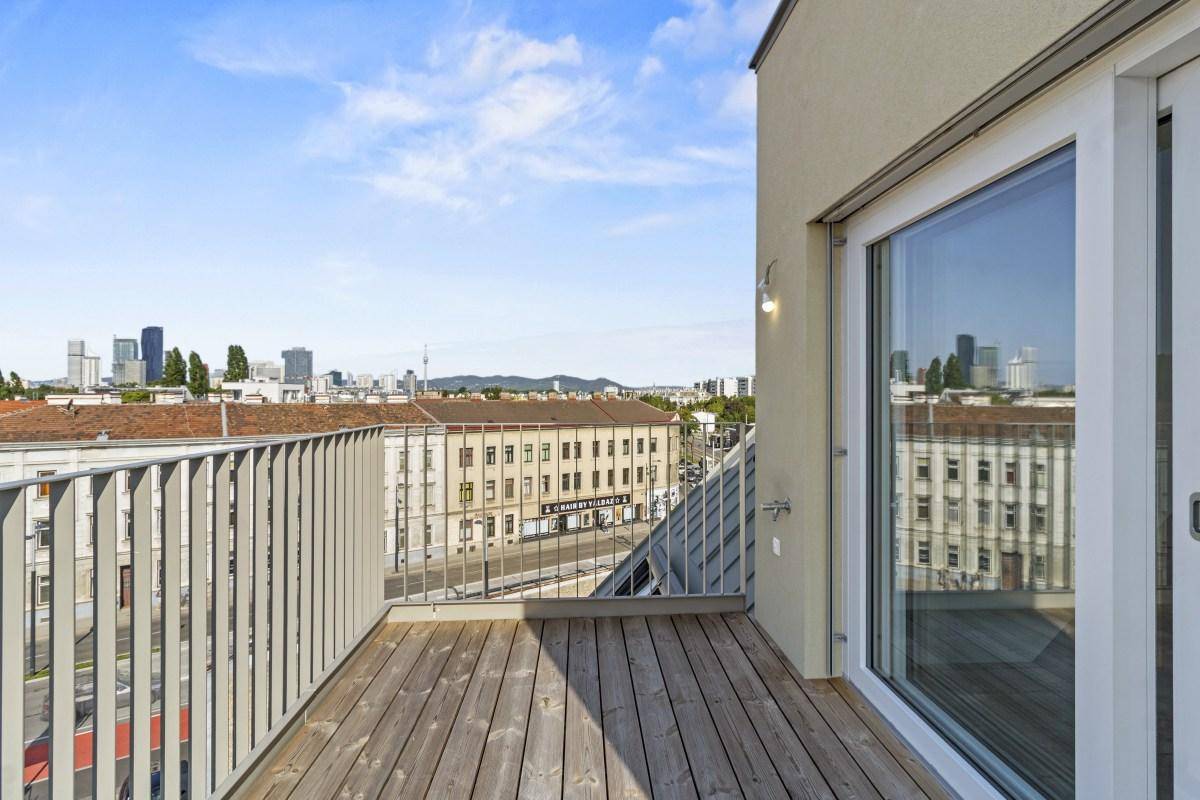 Moderner Balkon mit Holzboden und Panoramablick auf die Stadt und umliegende Gebäude.