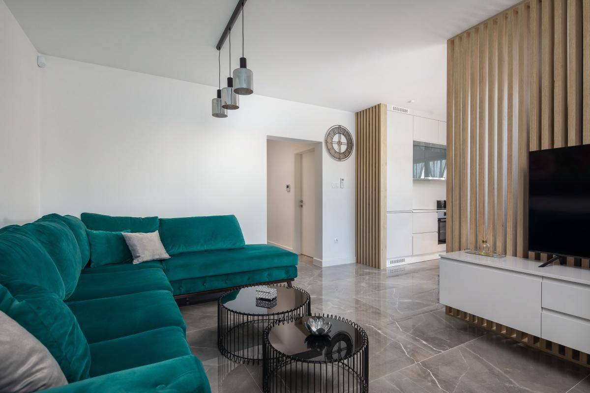 Moderner Wohnbereich mit bequemer Couch, stilvollen Tischen und Zugang zur Küche.