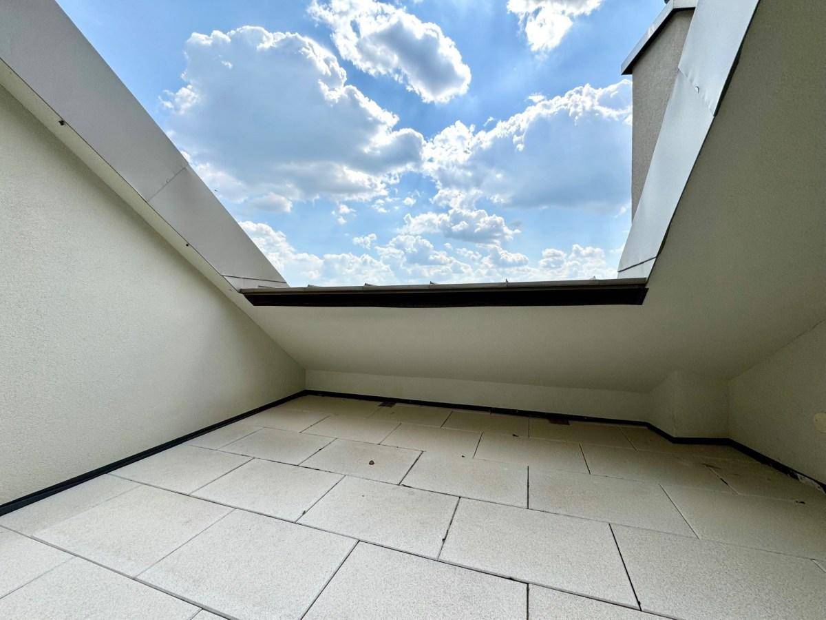 Kleiner Außenbereich mit Fliesenboden und offenem Blick in den blauen Himmel.