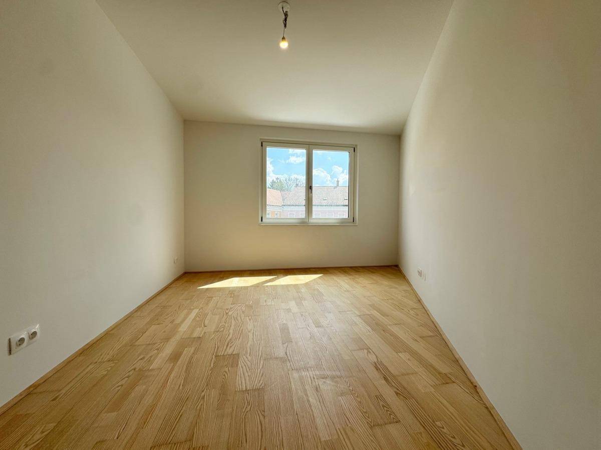 Ruhiges Schlafzimmer mit Parkettboden und viel Tageslicht, ideal zum Entspannen.