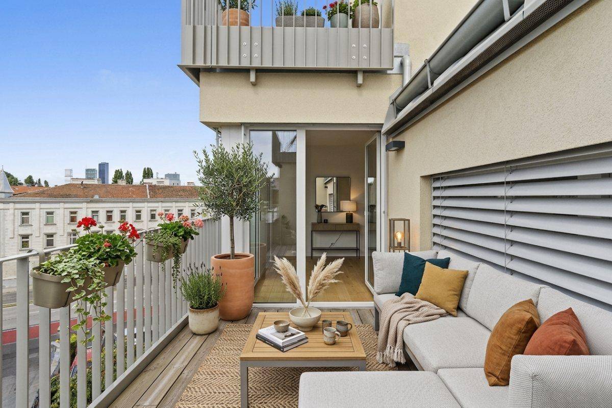 Möblierter Balkon mit Sitzbereich, Pflanzen und Blick auf die Stadt.