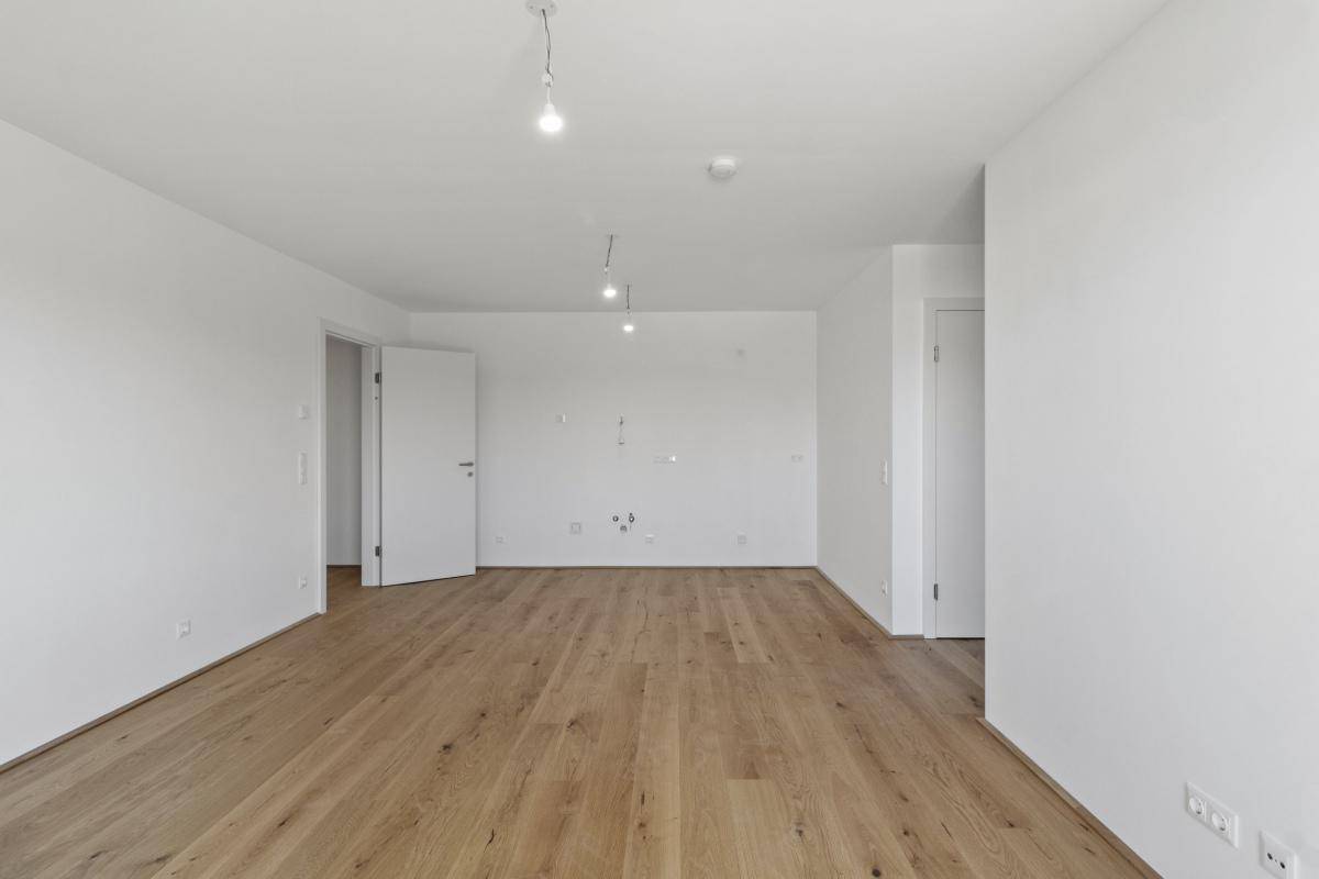 Leeres Schlafzimmer mit hellem Parkettboden und weißen Wänden, bereit zur individuellen Gestaltung.