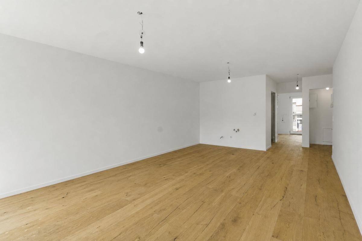 Geräumiger, unmöblierter Raum mit hellem Holzboden und weißen Wänden, bereit zum Einzug.