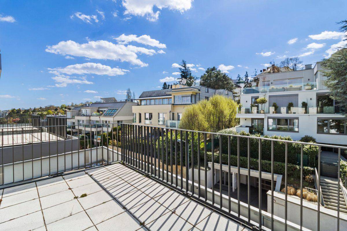 Balkon mit Blick auf moderne Wohngebäude und grüne Hügel in der Umgebung.