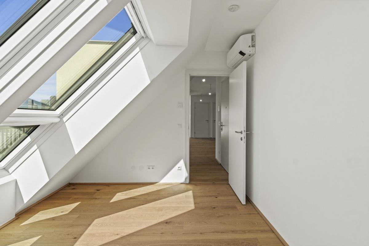 Dachgeschosszimmer mit schrägen Wänden, Dachfenstern und installierter Klimaanlage.