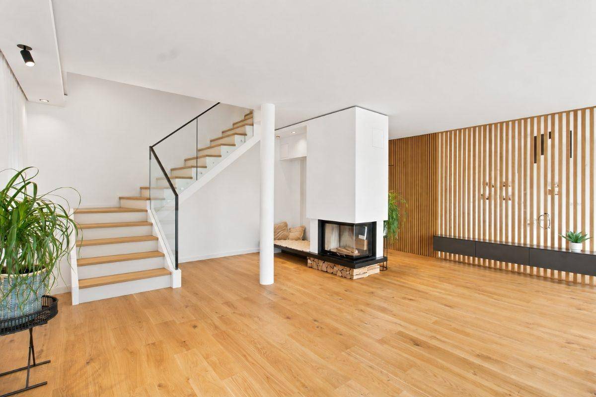 Heller Wohnbereich mit Holzfußboden, moderner Treppe und integriertem Kamin.