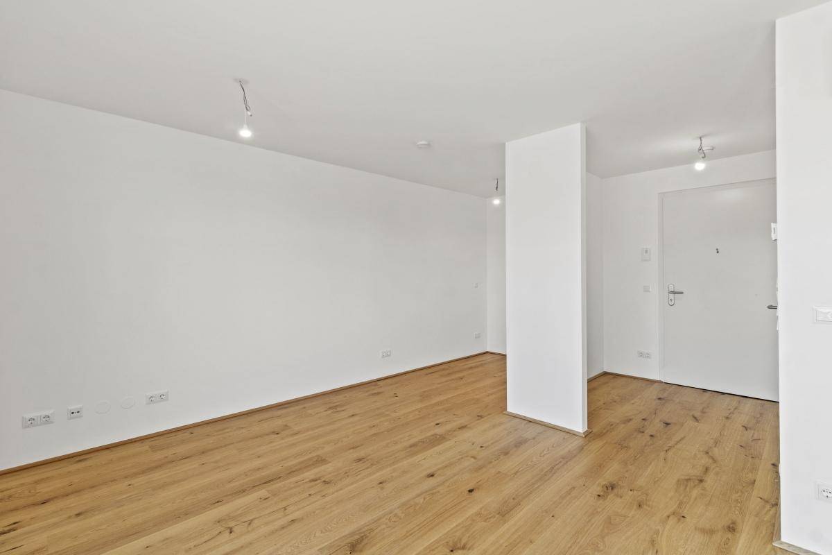 Leerer Raum mit Holzboden und weiß gestrichenen Wänden, bietet viel Gestaltungspotenzial.