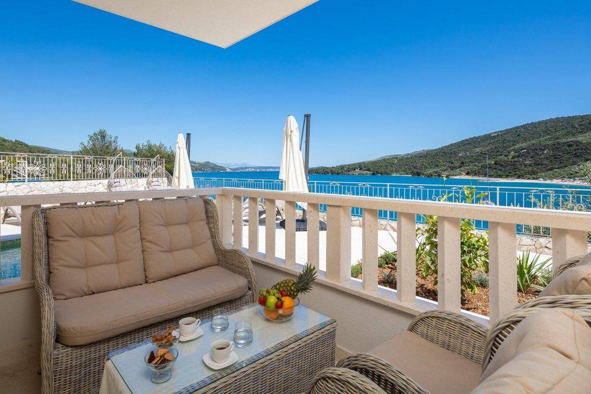 Möblierter Balkon mit Rattanmöbeln und einem weiten, beruhigenden Blick auf das Meer.