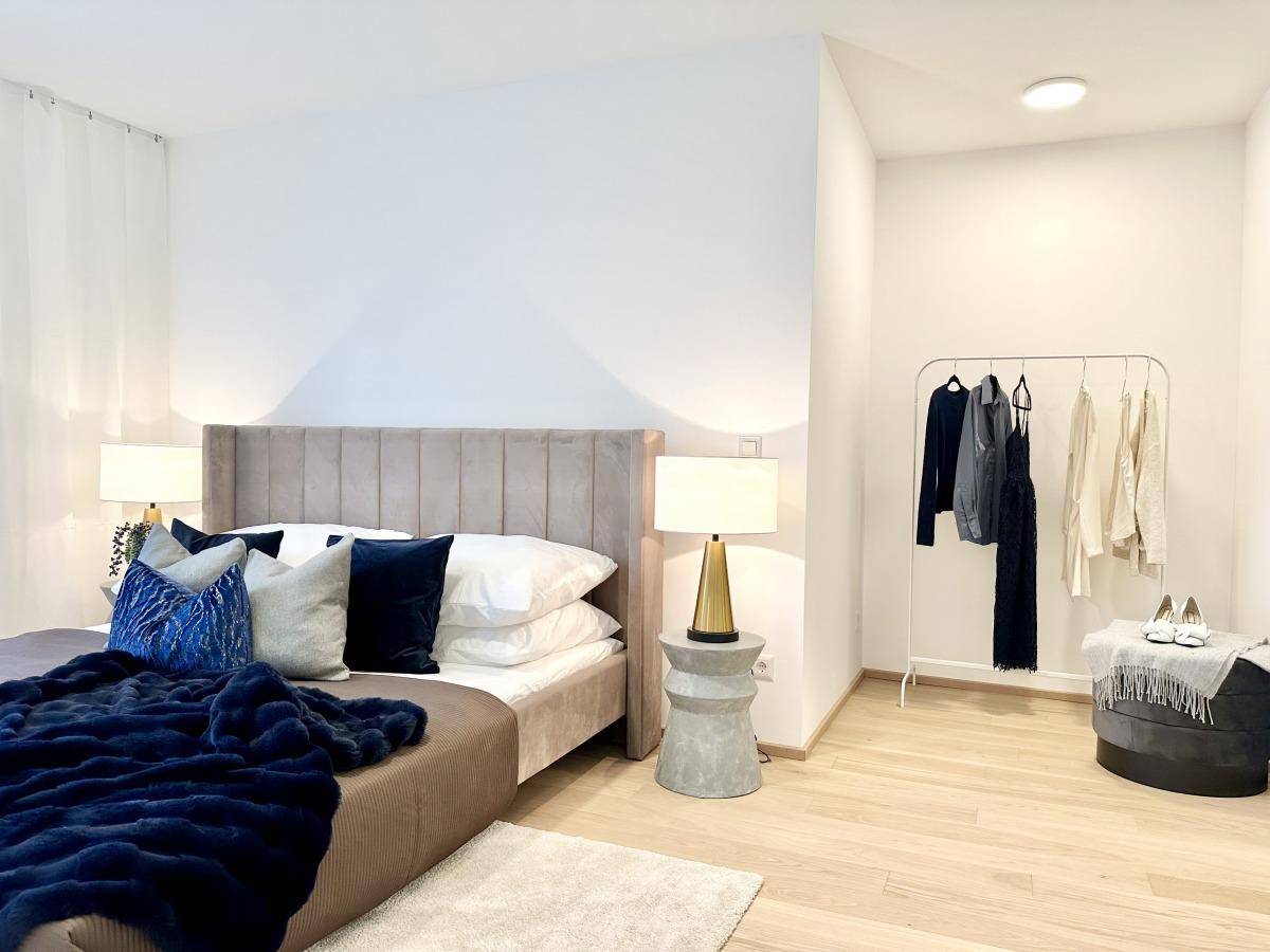 Geräumiges Schlafzimmer mit modernem Bett, Kleiderstange und gemütlicher Sitzecke.