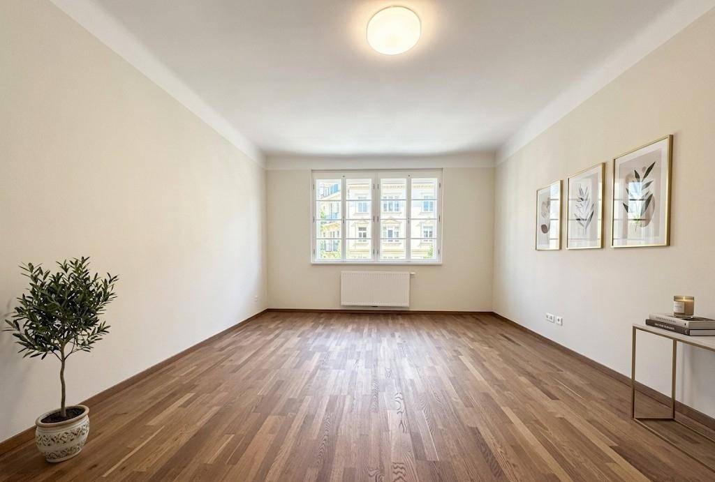 Helles, leeres Zimmer mit elegantem Holzparkettboden und einem Fenster mit Blick auf andere Gebäude.