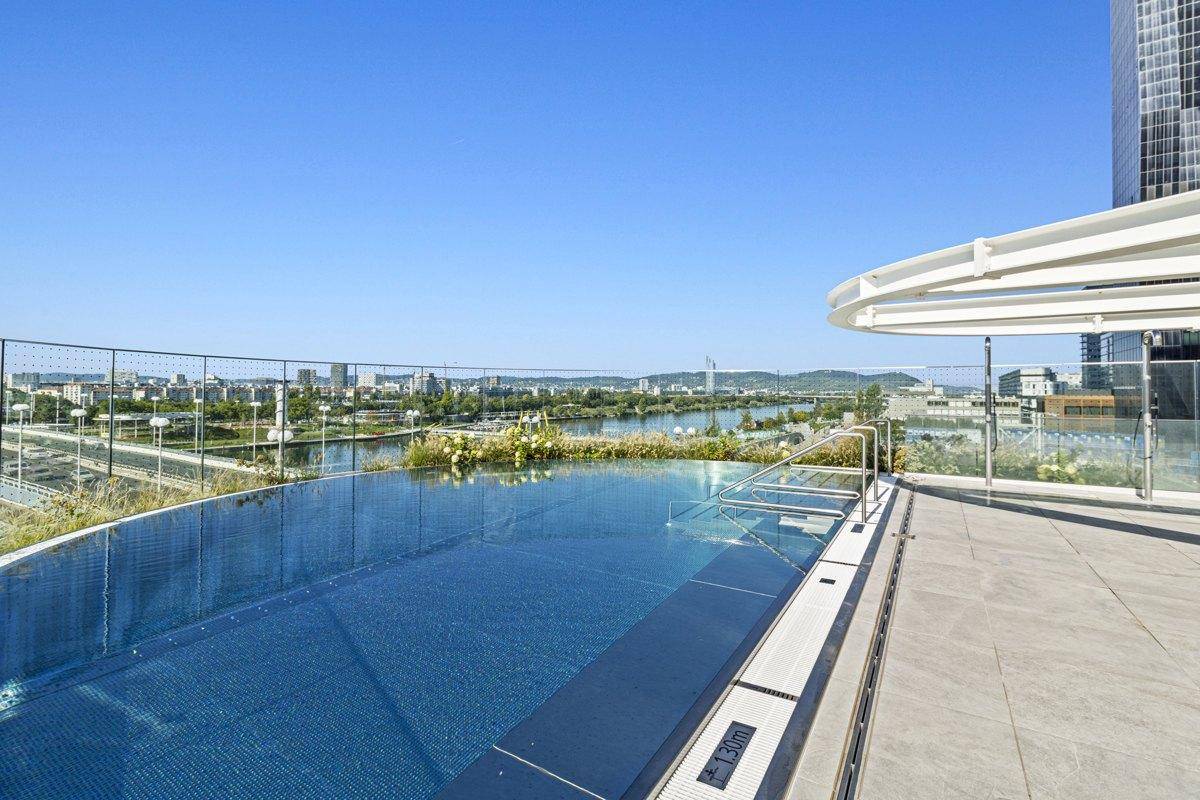 Dachterrassen-Infinity-Pool mit atemberaubendem Stadt- und Flussblick unter blauem Himmel.