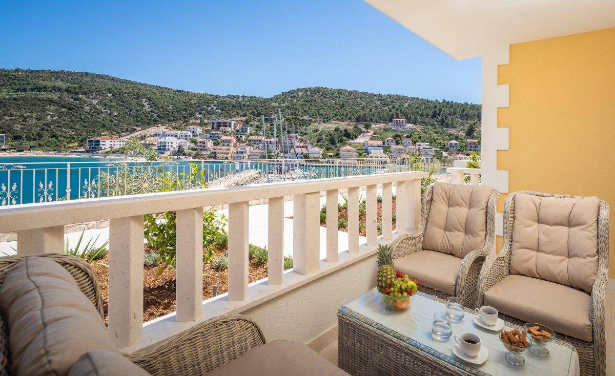 Gemütlicher Balkon mit Sitzgelegenheiten und einem malerischen Blick auf die Küstenstadt und das Meer.