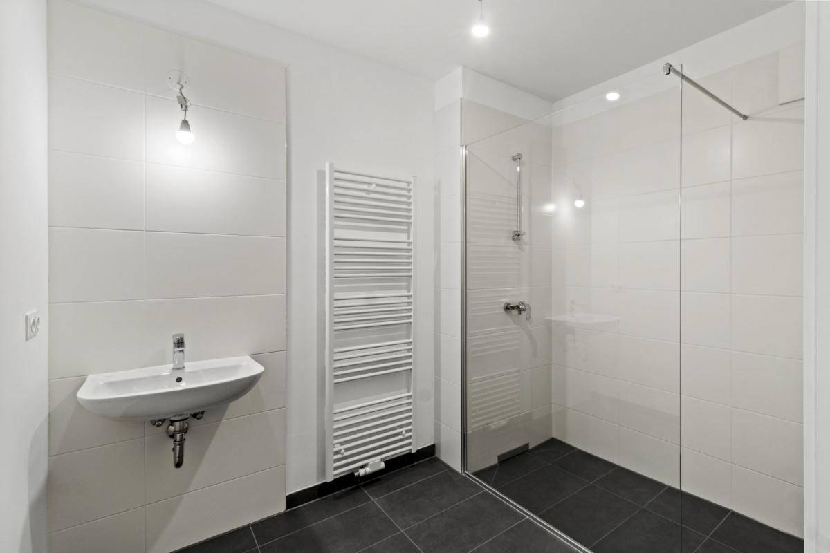 Modernes Badezimmer mit ebenerdiger Dusche, Einzelwaschbecken und Handtuchheizkörper.
