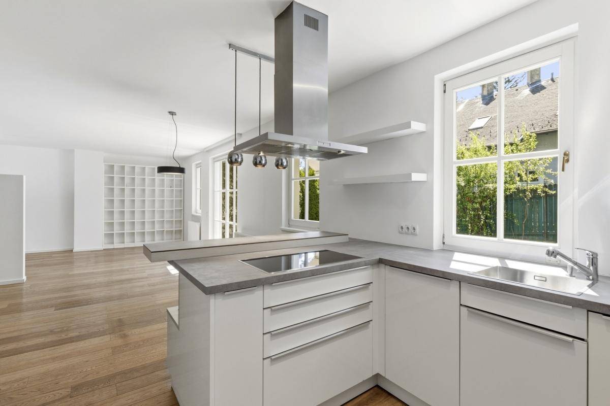 Moderne Küche mit Kücheninsel, Induktionskochfeld und Spüle, offen zum Wohnbereich.