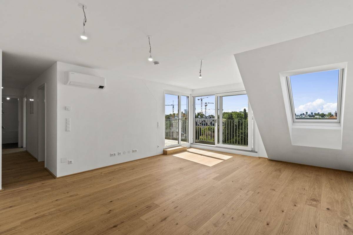 Geräumiger Wohnbereich mit Holzboden, Klimaanlage und Zugang zu einem Balkon mit Weitblick.
