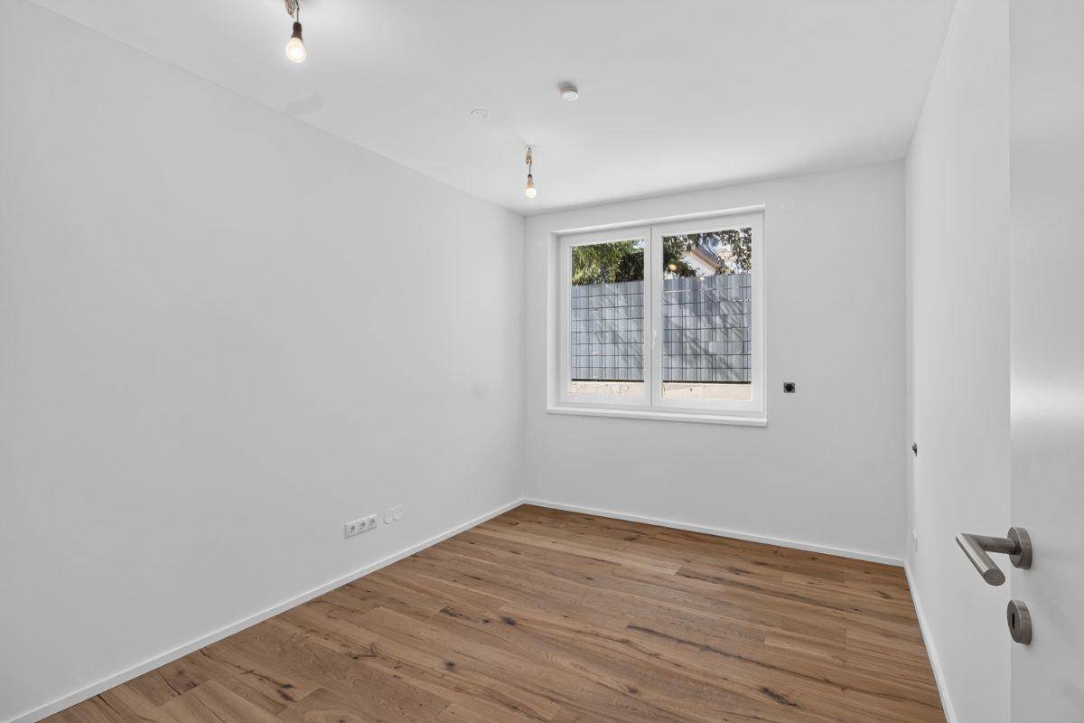 Modernes Schlafzimmer mit Holzboden und weiß gestrichenen Wänden, bereit zum Einzug.