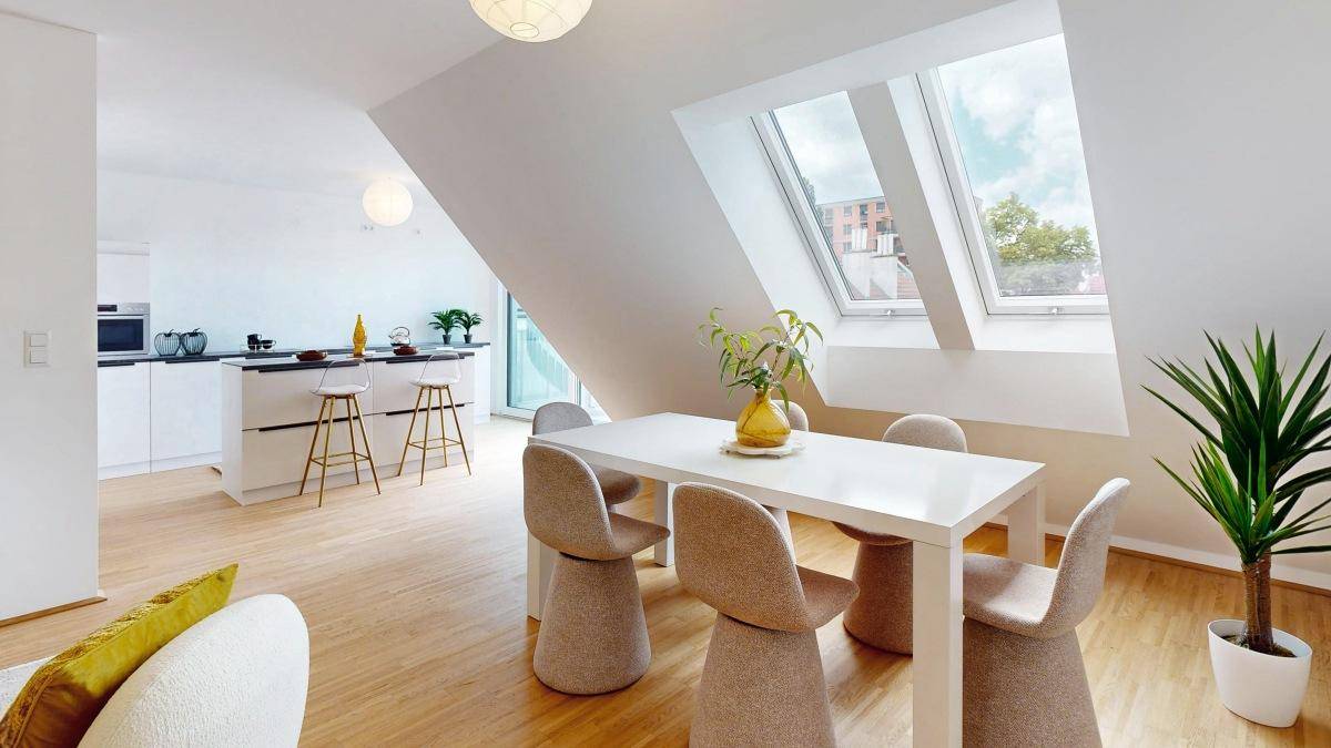Offener Wohn-Essbereich mit Dachschrägen, Esstisch und Blick auf die moderne Küche.