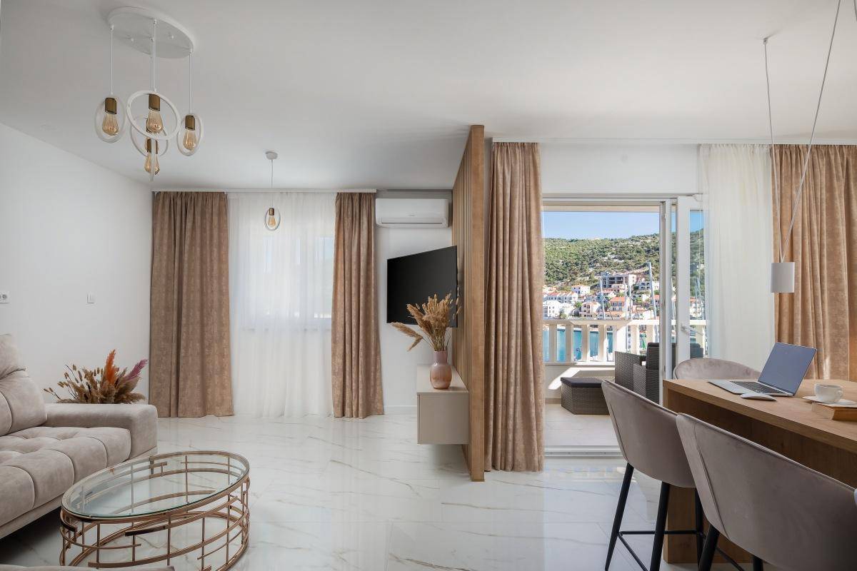 Heller Wohn- und Essbereich mit modernen Möbeln, Fliesenboden und Zugang zu einem Balkon mit Meerblick.