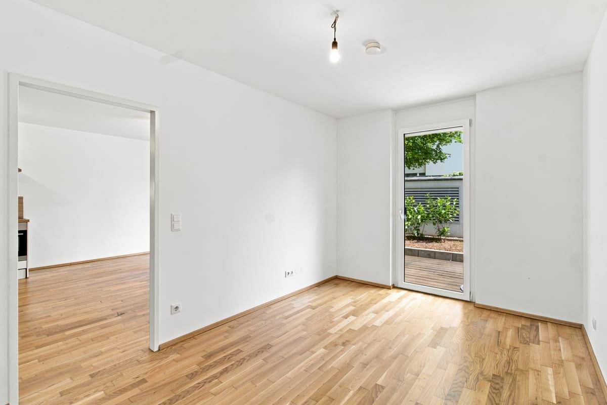 Helles Schlafzimmer mit Holzboden und Zugang zu einem privaten Außenbereich.