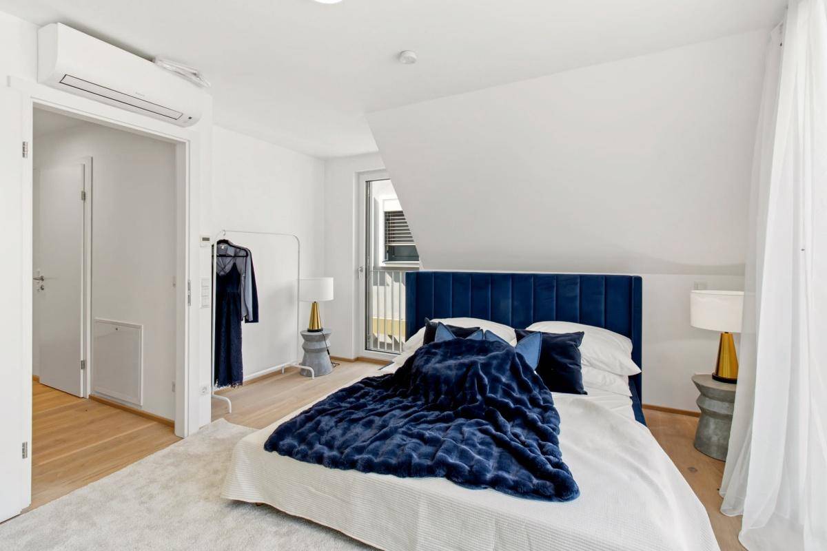 Modernes Schlafzimmer mit Dachschräge, Klimaanlage und Zugang zu einem französischen Balkon.