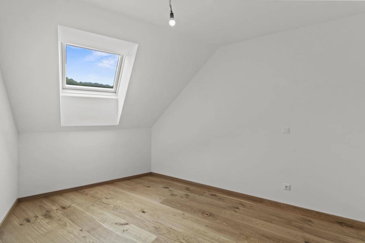 Heller Raum mit Holzboden, Dachschräge und einem Oberlichtfenster, ideal als Arbeitszimmer.