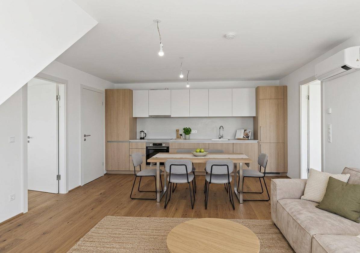 Moderne Küche mit hellen Holz- und weißen Fronten, integriertem Essbereich und Holzboden.
