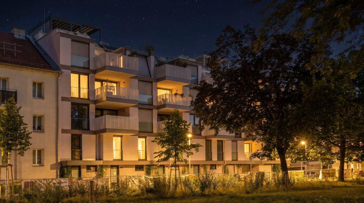 Ansicht der modernen Wohnanlage bei Nacht mit beleuchteten Innenräumen.