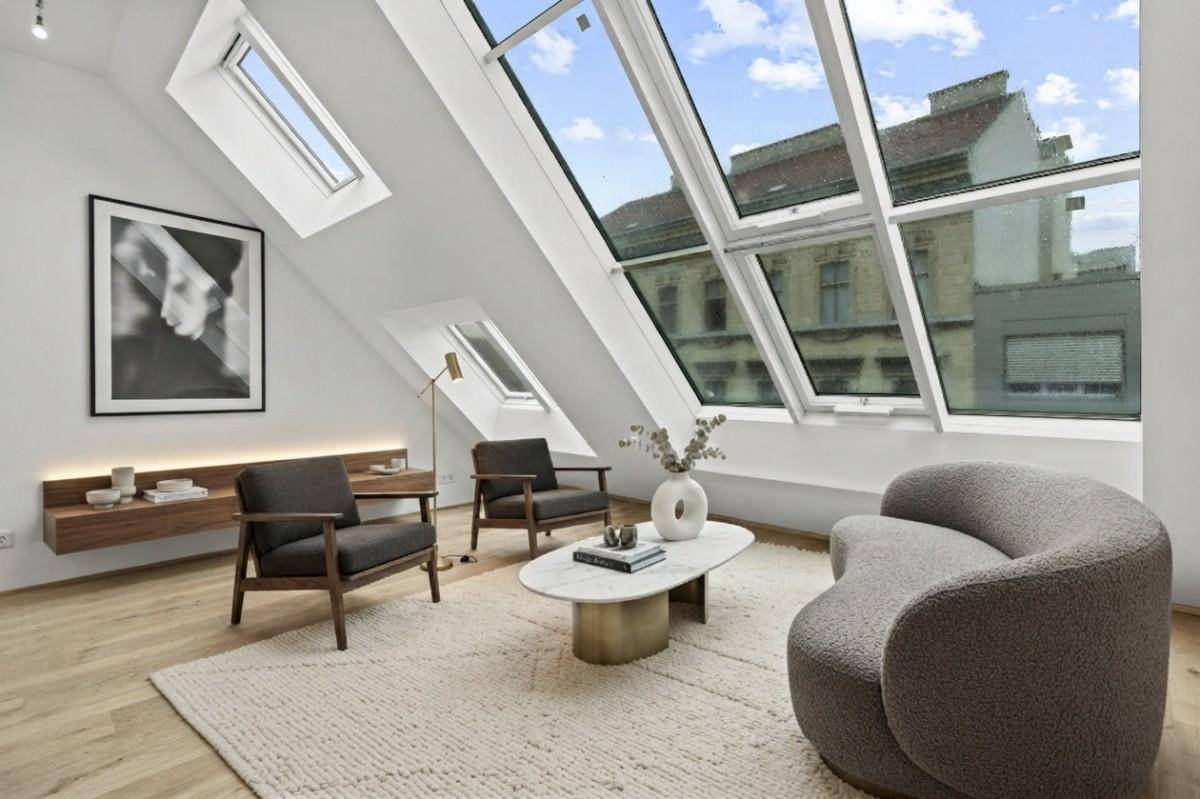 Lichtdurchflutetes Wohnzimmer im Dachgeschoss mit schrägen Wänden und stilvoller Einrichtung.