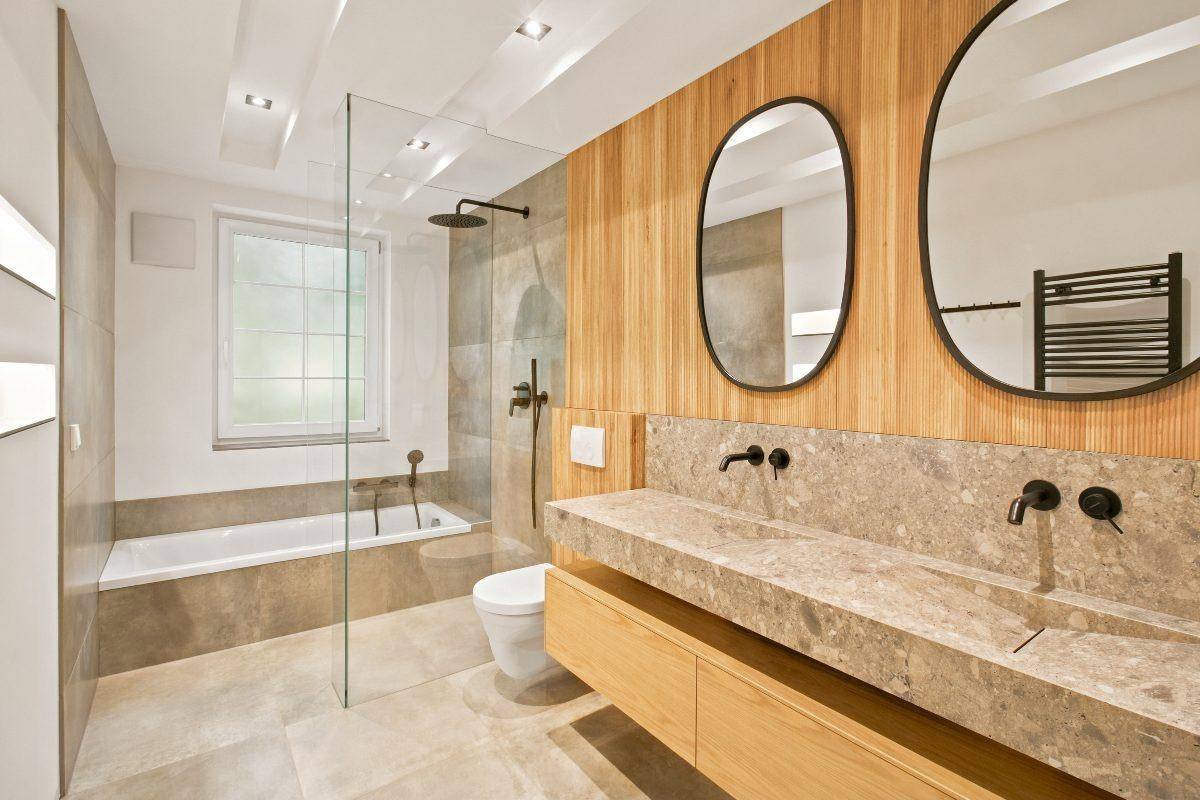 Modernes Badezimmer mit Doppelwaschbecken, Badewanne, Dusche und Holzdetails.