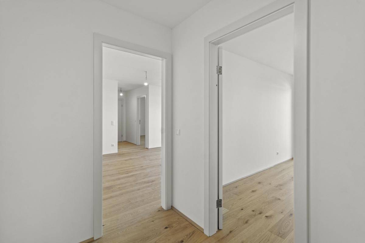 Heller Flur mit Holzboden, der zu verschiedenen Zimmern der Wohnung führt.