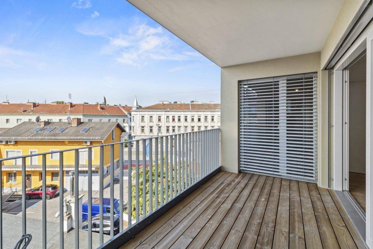 Geräumiger Balkon mit Holzbelag und Blick auf die umliegende Stadt.