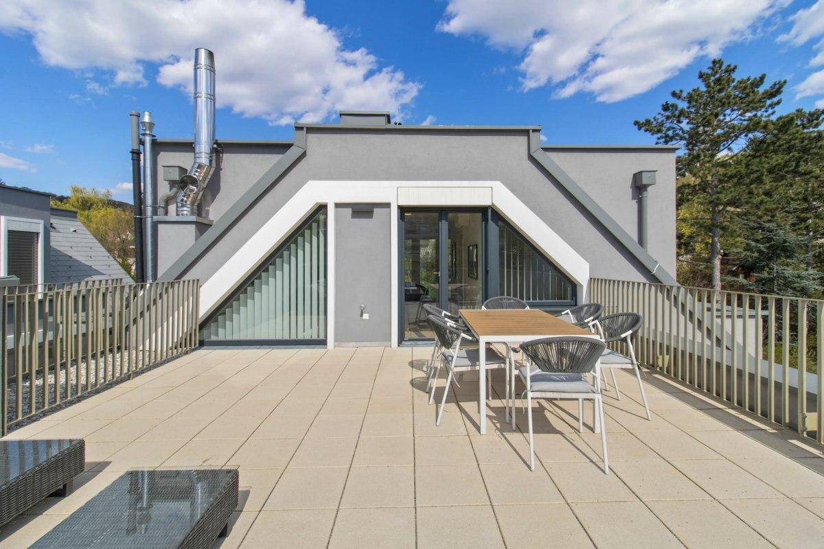 Dachterrasse mit Essbereich und Zugang zum Innenbereich des modernen Gebäudes.