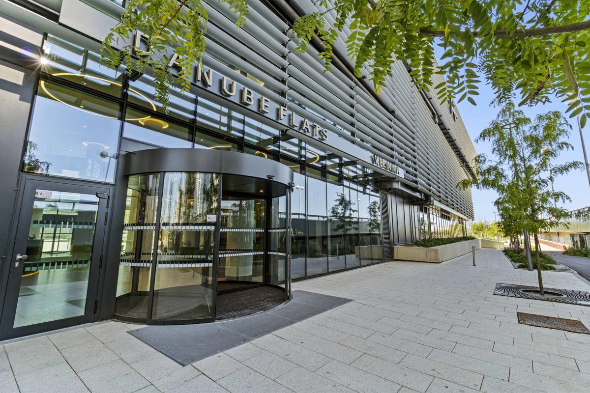 Moderner Gebäudeeingang mit Drehtür und Glasfassade des Danube Flats Komplexes.