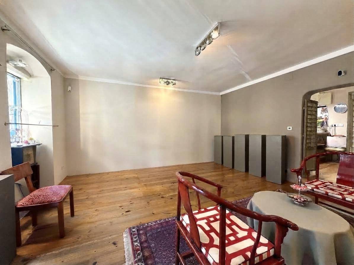 Geräumiger Geschäftsraum mit Holzdielenboden, Fenstern und einer Mischung aus modernen und traditionellen Möbeln.