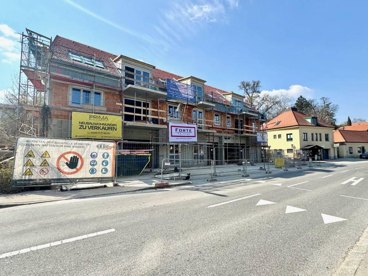 Baustelle eines Neubauprojekts mit Gerüst und Hinweisschildern zur Sicherheit.