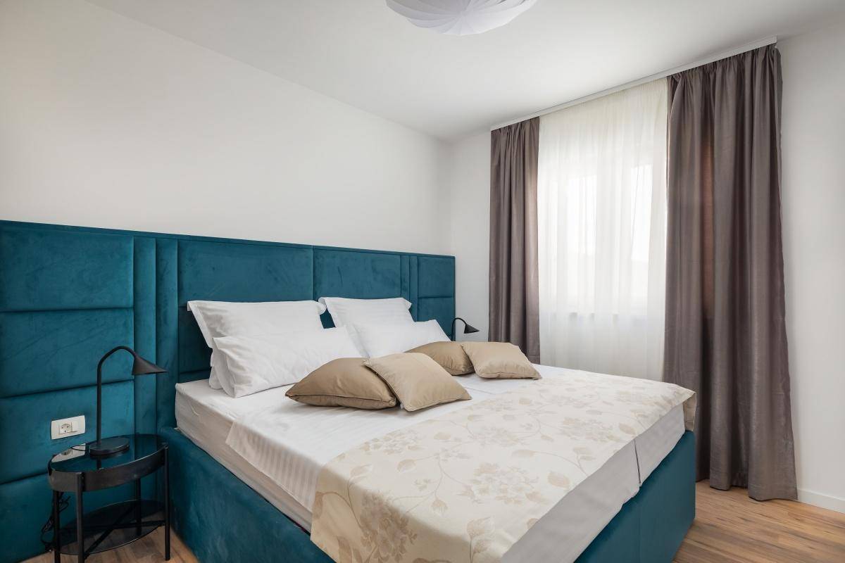 Gemütliches Schlafzimmer mit großem Doppelbett, blauer Polsterung und Holzboden.